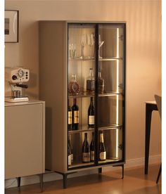 a cabinet with wine bottles and glasses in it next to a dining room table on the floor