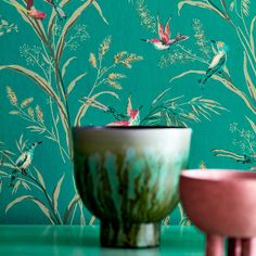 two vases sitting next to each other on a table in front of a green wall