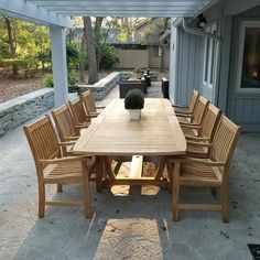 a wooden table with chairs around it on a patio next to an outdoor living area