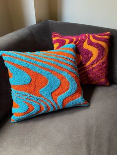 two colorful pillows on a gray couch