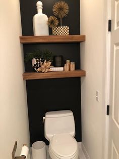 a white toilet sitting in a bathroom next to a wooden shelf