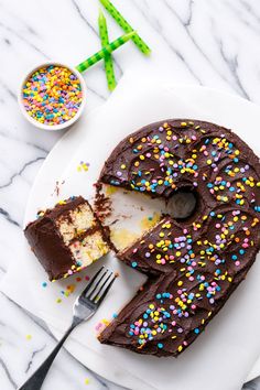 a chocolate cake on a plate with one slice cut out and sprinkles