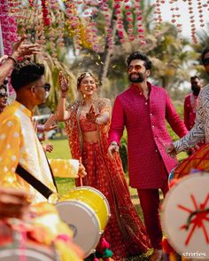 a man and woman are walking down the aisle with drum players in front of them