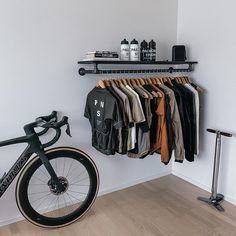 a bicycle is parked next to a rack with shirts on it