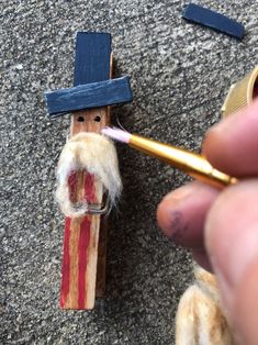 a person holding a toothbrush in front of a small wooden toy with a cross on it