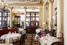 a dining room with tables, chairs and chandeliers on the walls is shown