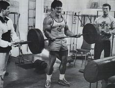 a man holding a barbell while standing next to another man