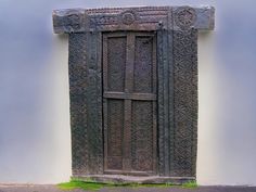 an old wooden door on the side of a building with grass in front of it