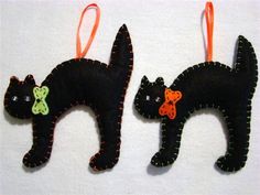 two black cats are hanging from orange string