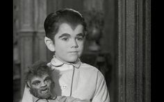 a young boy is holding a monkey in his arms and looking at the camera with an angry look on his face