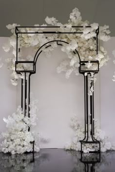 an arch with white flowers on it in the middle of a room filled with black and white walls