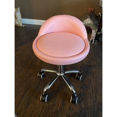 a pink office chair sitting on top of a hard wood floor next to a cat