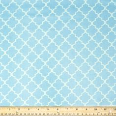 a blue and white fabric with an intricate design on the side, in front of a ruler