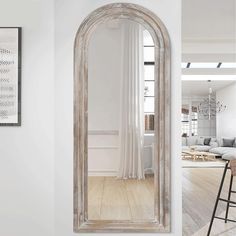 a large white mirror sitting on top of a wooden floor