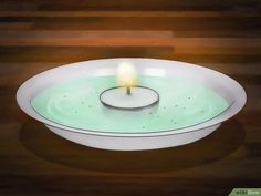 a lit candle in a bowl on a table