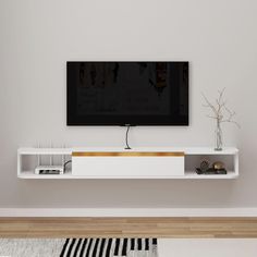 a flat screen tv mounted to the side of a wall above a white entertainment center