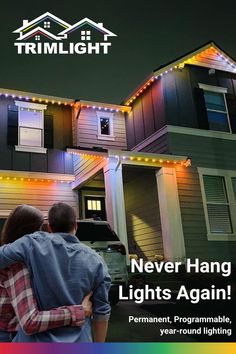 two people standing in front of a house with christmas lights