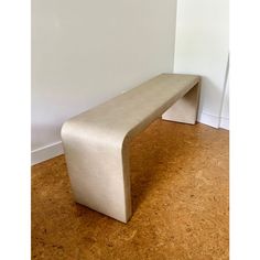 a white bench sitting on top of a hard wood floor next to a white wall