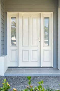 the front door to a house with two white double doors and sidelights on either side