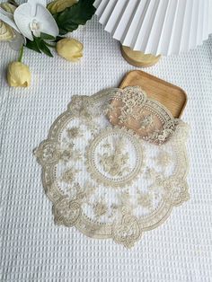 a white table cloth with lace on it next to some flowers and a wooden cutting board