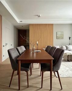 a dining room table and chairs in front of a living room with wood paneling