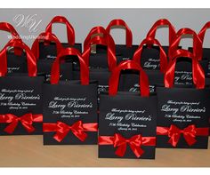 small black and red bags with red ribbon on them are sitting on a table in front of the camera