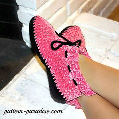 a woman's feet wearing pink slippers with black bows and a crochet pattern