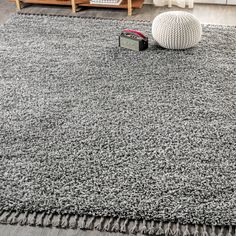 a gray rug with fringes on the floor in a living room