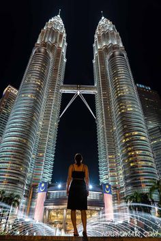 a woman standing in front of two tall buildings with the words 8 things to do in kl