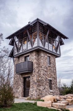 a stone tower with windows and balconies on the top is surrounded by rocks