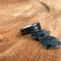 two rings sitting on top of a wooden table next to each other with rocks in the middle