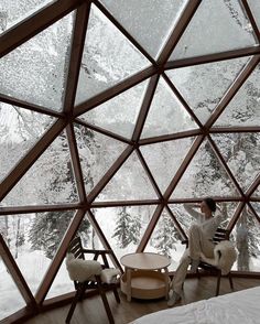 a person sitting in a room with snow on the ground and trees behind them,