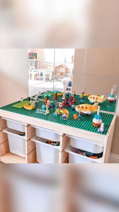 a lego table with toys on it in front of a mirror and toy storage bins