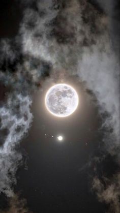 an image of the moon in the sky with clouds around it and two bright lights