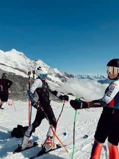 three people on skis in the snow with mountains in the backgroung