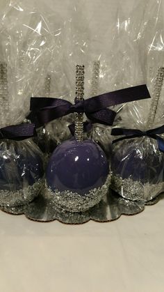 three chocolate candies wrapped in plastic and tied with a purple ribbon on a silver platter