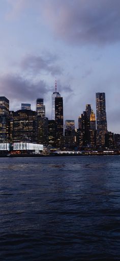 the city skyline is lit up at night as seen from across the water in front of a large body of water