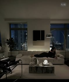 a woman laying on top of a white couch in a living room