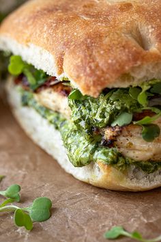 a close up of a sandwich on a piece of bread with greens and meat in it