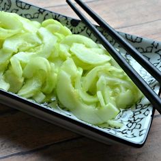 two chopsticks sit on top of a plate with green vegetables and noodles in it