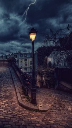 a street light sitting on top of a cobblestone road under a cloudy sky