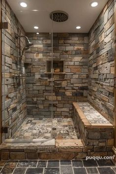 a walk in shower with stone walls and tile flooring, along with two benches