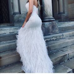 a woman in a white dress is standing on some steps