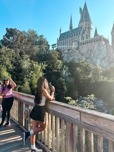 two girls standing on a bridge looking at hogwarts castle in the back ground