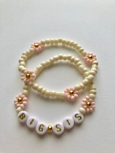 two white and pink beaded bracelets sitting on top of each other with gold beads