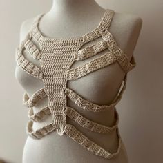 a white mannequin with crochet on it's chest and back