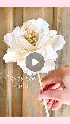 a person holding a white flower in their hand with the words flores con cinta on it