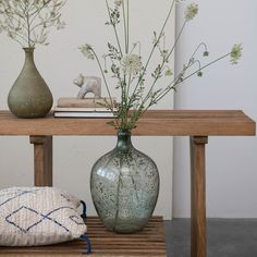 two vases sitting on a table with flowers in one and a pillow on the other