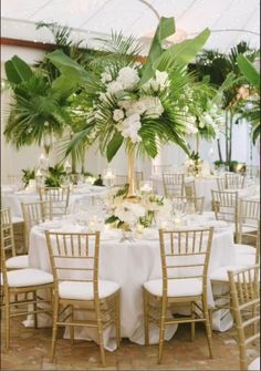 a table with white flowers and greenery is set up for a wedding reception in a tent