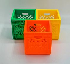 three plastic baskets sitting on top of a white table next to an orange and green container